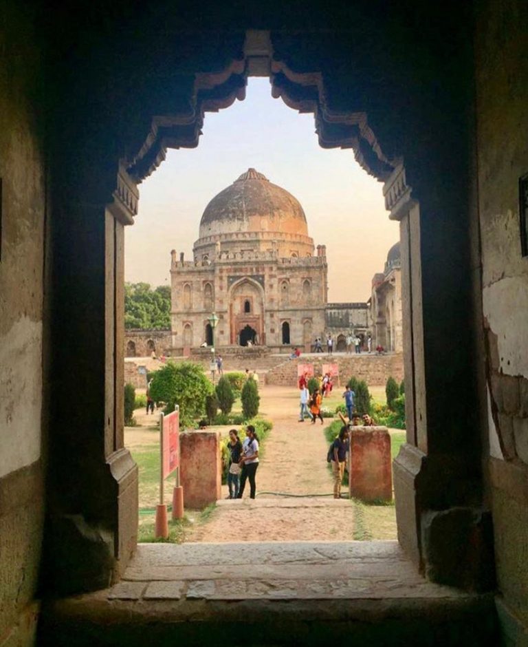 Domed tomb seen through a carved archway at the end of a garden path