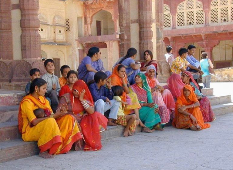 Women and children in bright saris on the steps of a palace courtyard