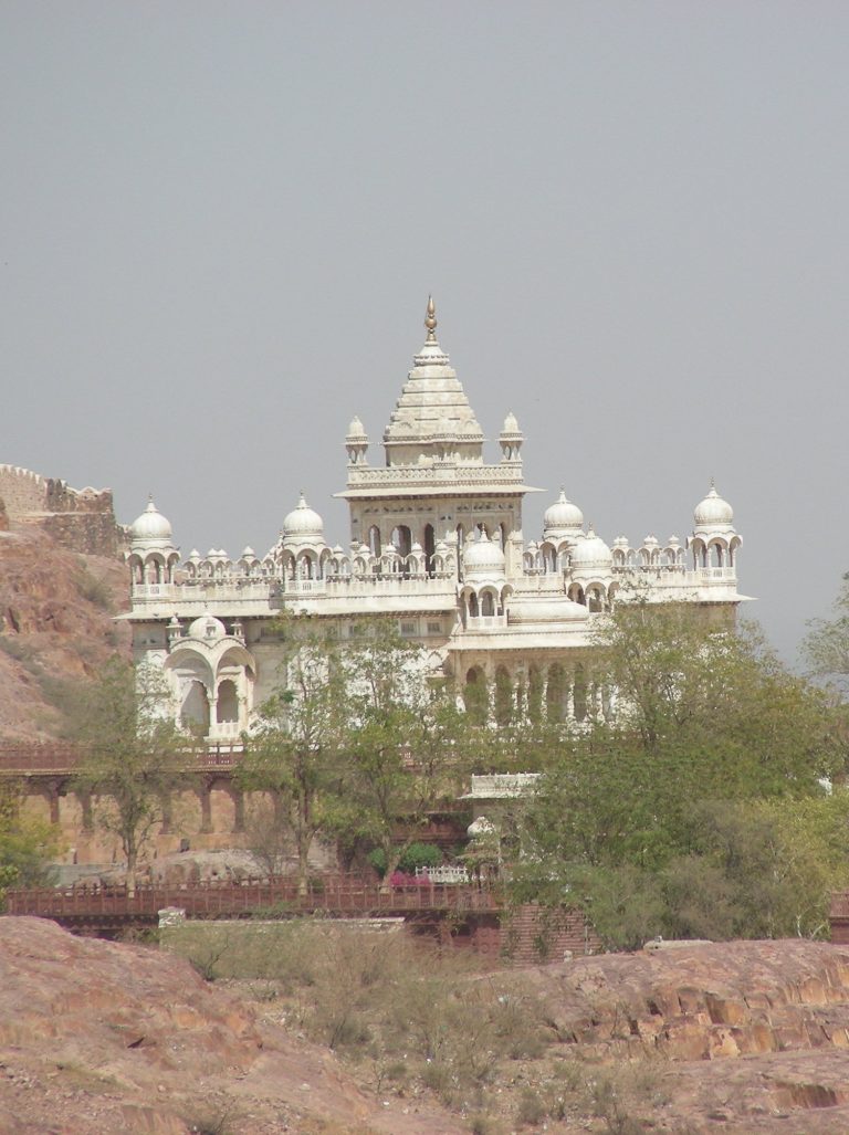 White marble temple with carved spires rising above the trees