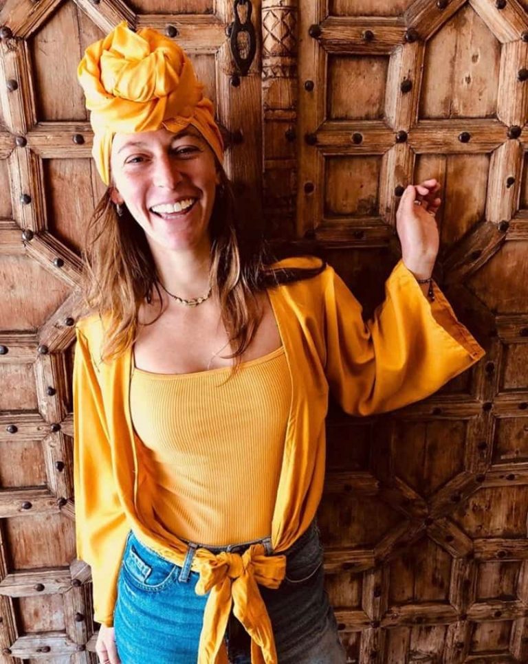 Laughing woman in marigold silks before carved timber doors