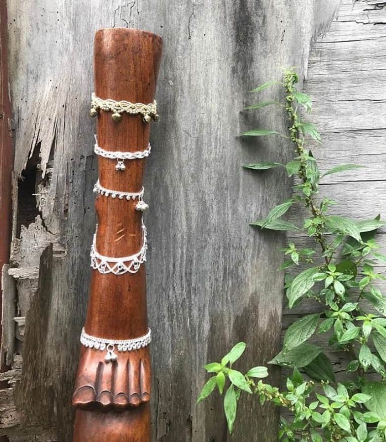 Anklets of shell and bead on a carved wooden foot
