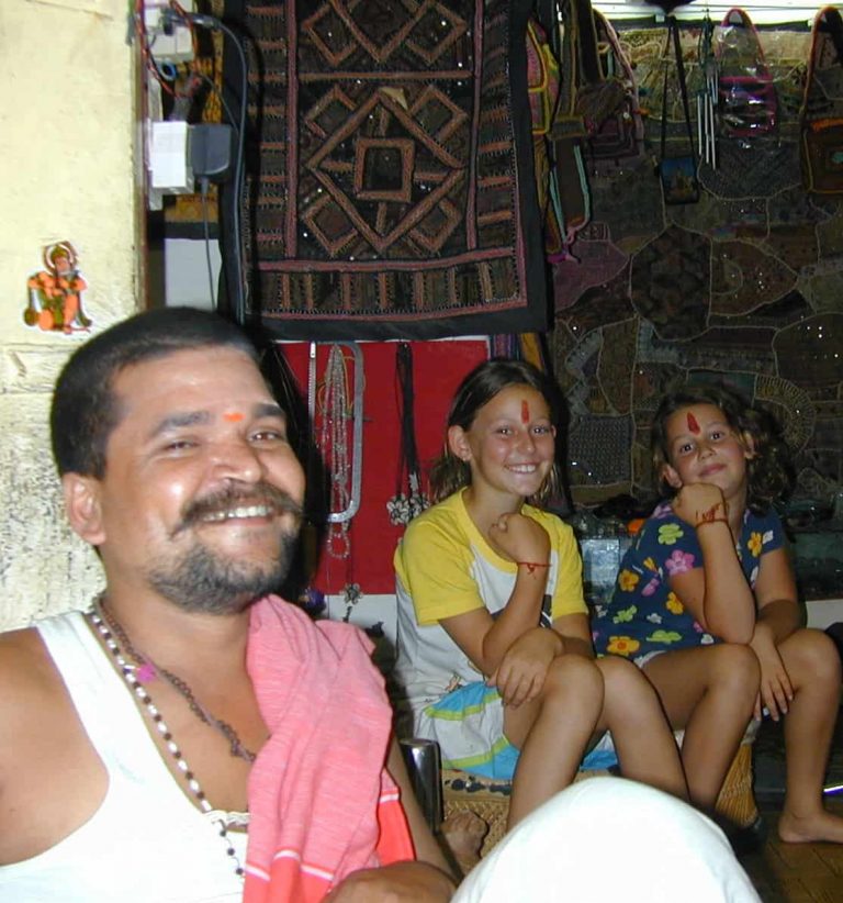 Smiling stallholder with two young visitors among the wall hangings