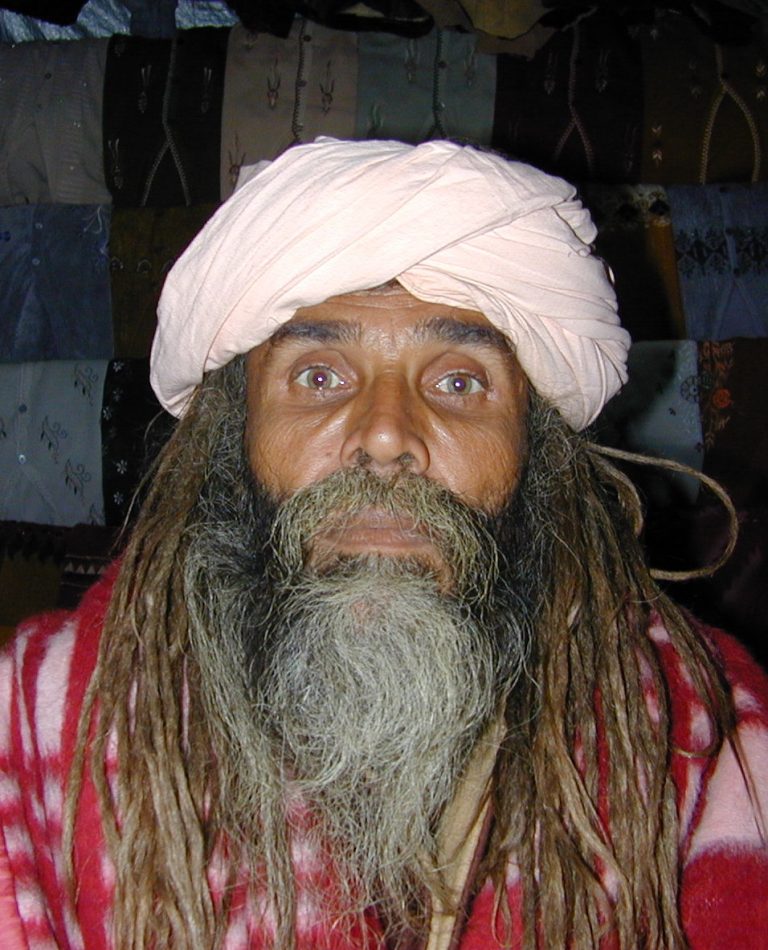 Dreadlocked baba in a blush-pink turban, eyes wide