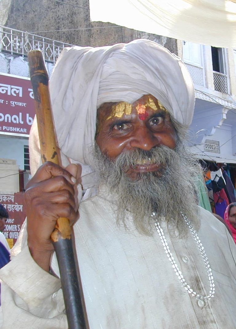 White-turbaned elder with a flowing beard smiling in the bazaar