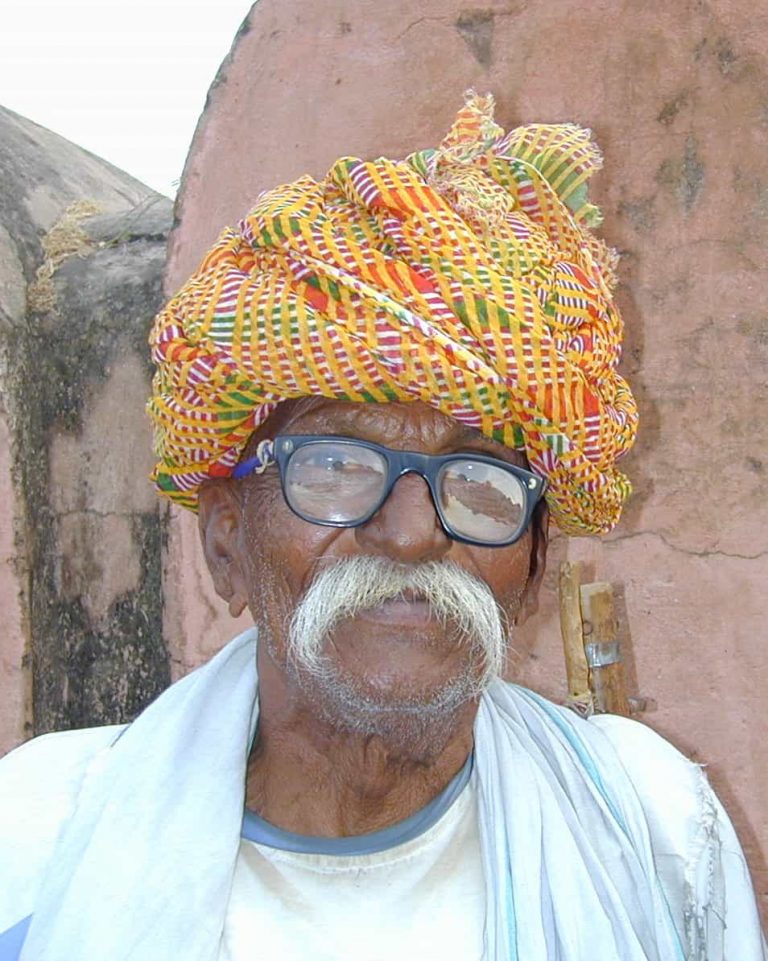 Elder in spectacles and a woven turban of every colour