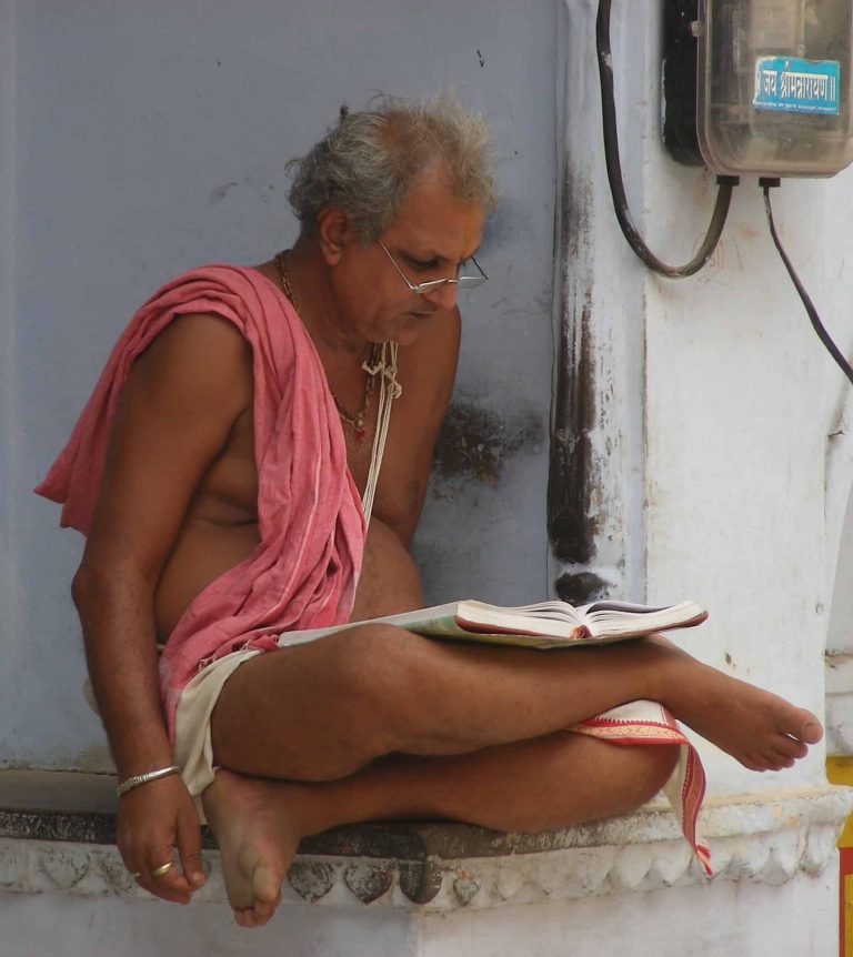 Reading scripture in a rose shawl on a temple ledge